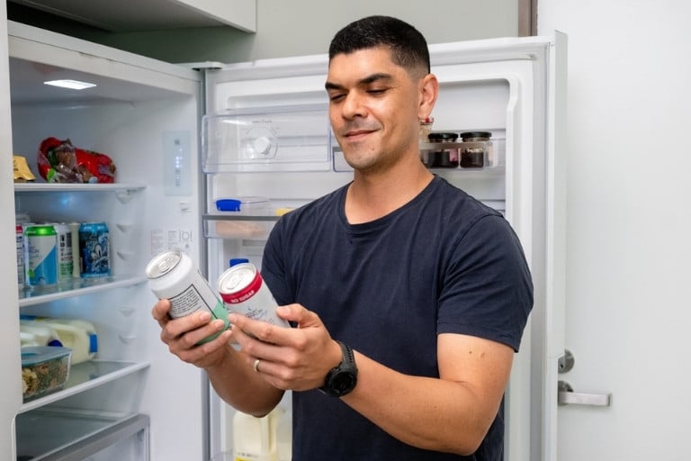 Man deciding between two drink options from the fridge
