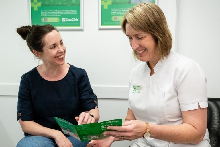 Female pharmacist and female patient reading vaccination brochure together