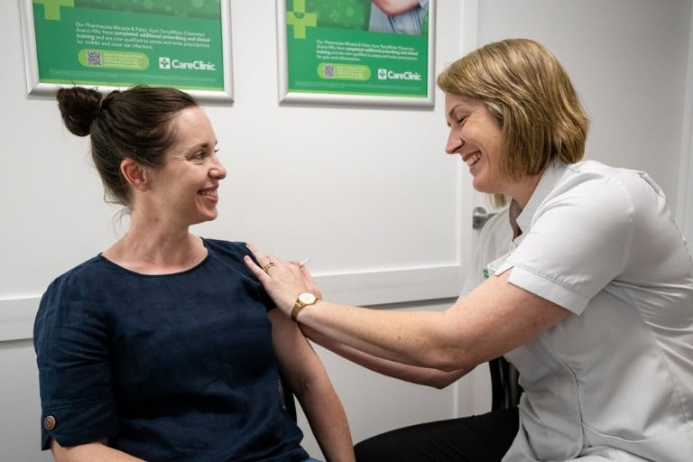 Pharmacist providing vaccination injection to female adult patient