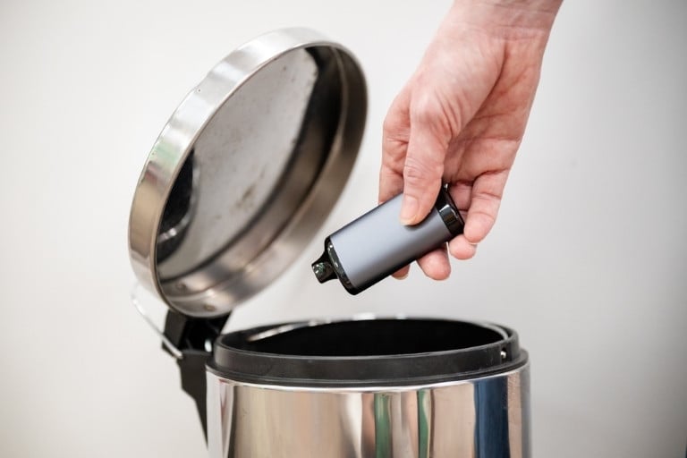 Person discarding a vap into a rubbish bin