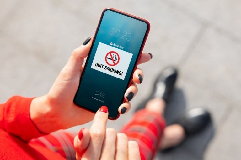 Person holding a phone with a Quit smoking app on the screen
