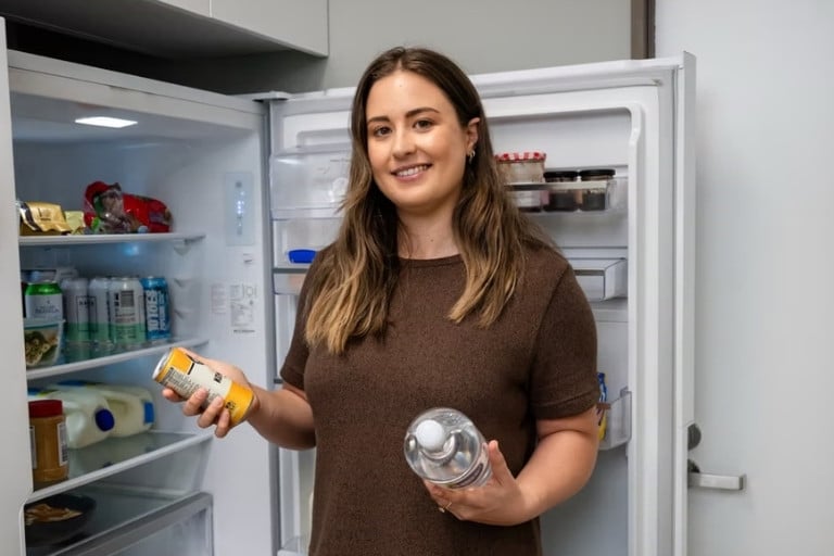 Woman deciding between water and an alcoholic drink from the fridge