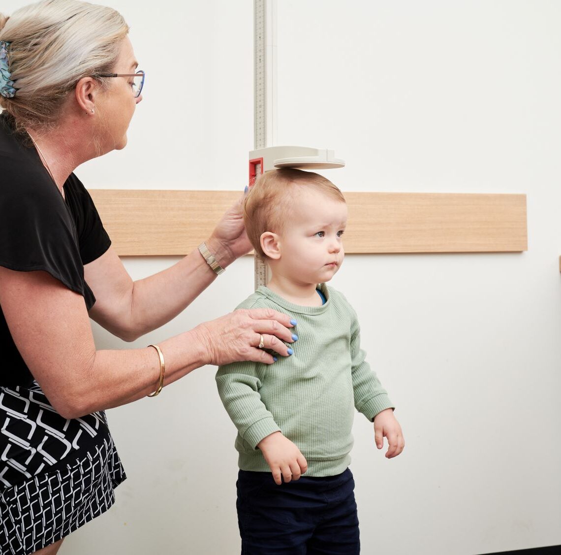 A health professional measuring the height of a toddler