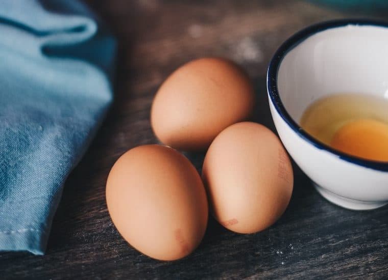 Close up of three eggs and one cracked egg in a bowl