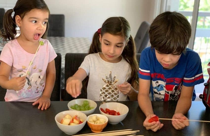 Three Queensland kids making and eating fruit kebabs