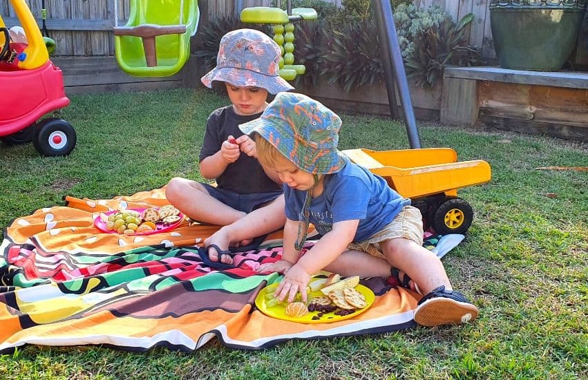 Two young brothers in Queensland eating healthy snacks in their backyard