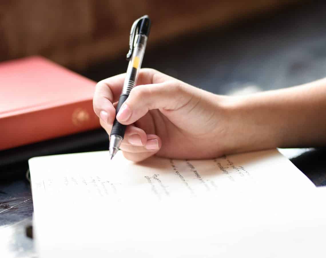 Close up of a person writing in a journal