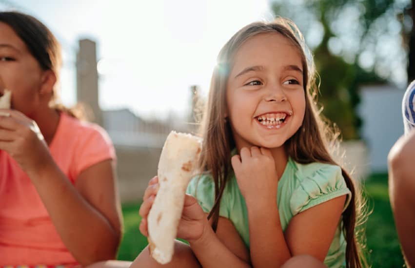 Young girl eating wrap and smiling