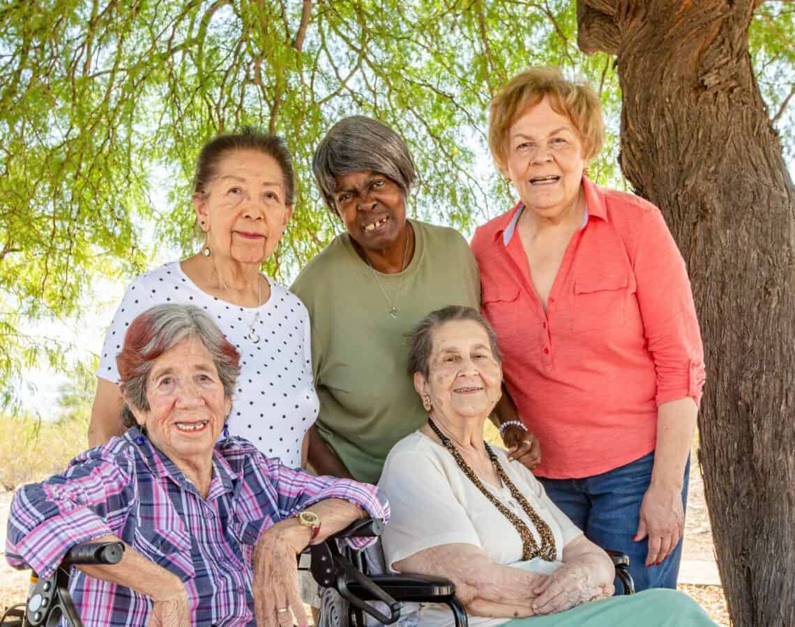 5 mature women gathered outside under a tree