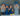 4 children in school uniforms eating pieces of fruit in front of a big fruit bowl