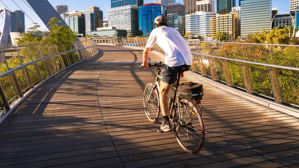 A man cycling on a city bridge