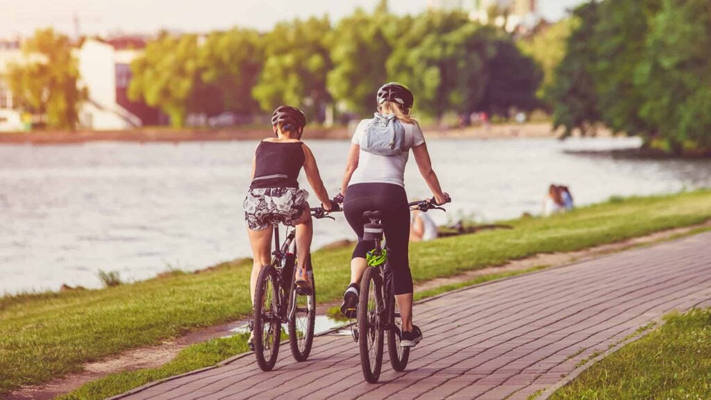 Cyclists ride on the bike path in the city by a river