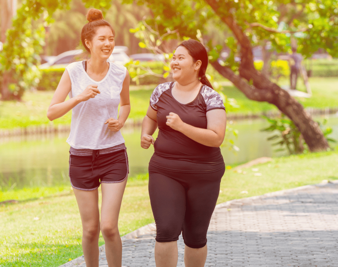 Two young women running along a path in a park