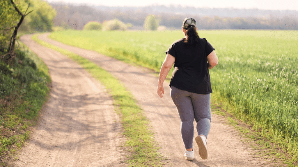 A woman is walking down a path next to a green field