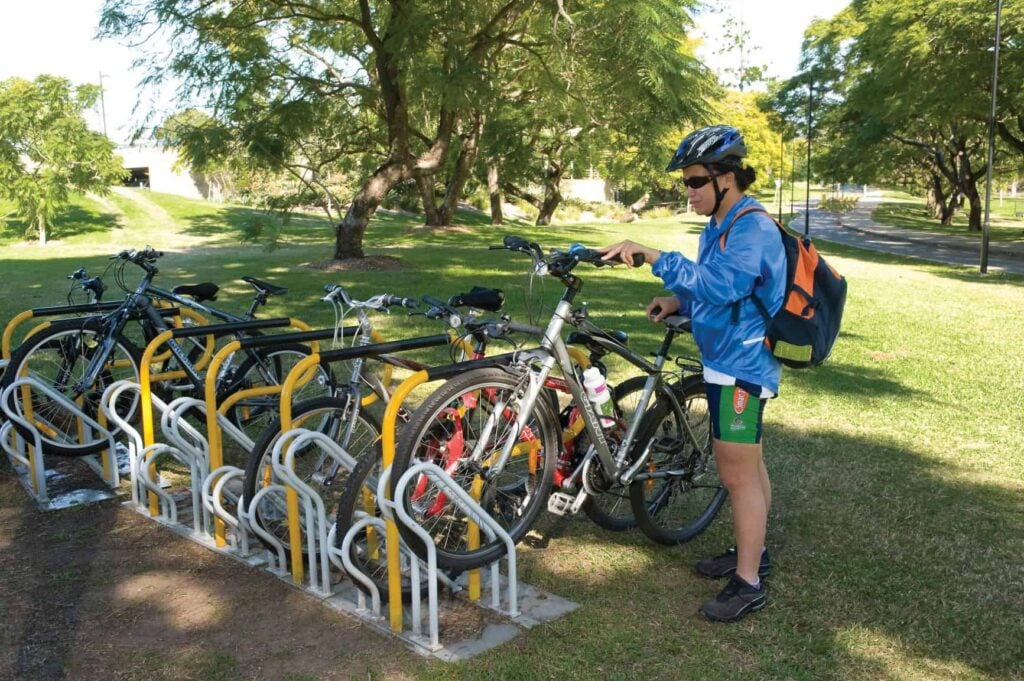 A woman wearing a bike helmet putting a bike into a bike rack