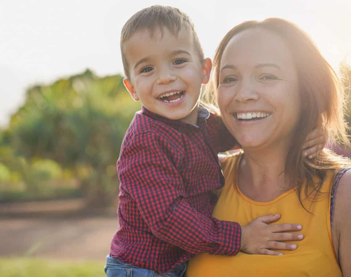 A young mother holding her son in her arms, both smiling