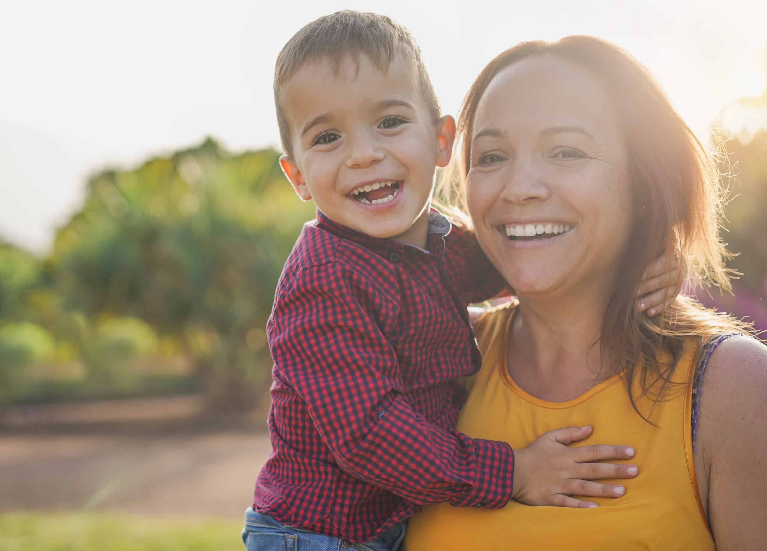 A young mother holding her son in her arms, both smiling