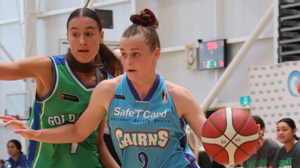 2 young females playing basketball on in indoor basketball court