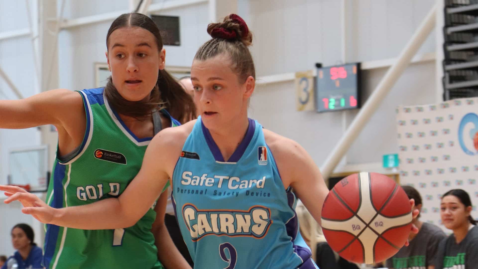 2 young females playing basketball on in indoor basketball court