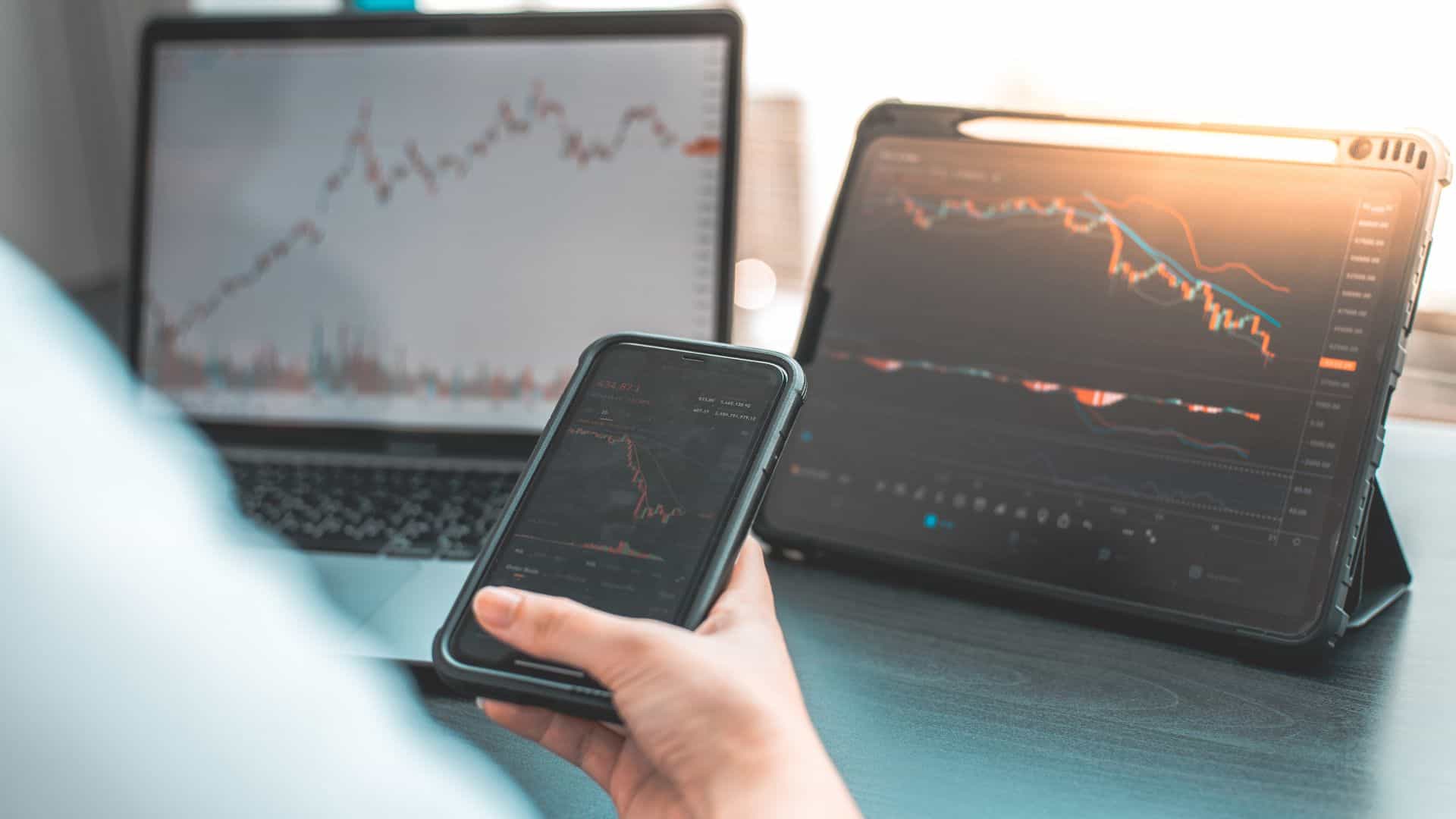 Laptop, tablet and mobile phone screens displaying graphs and data