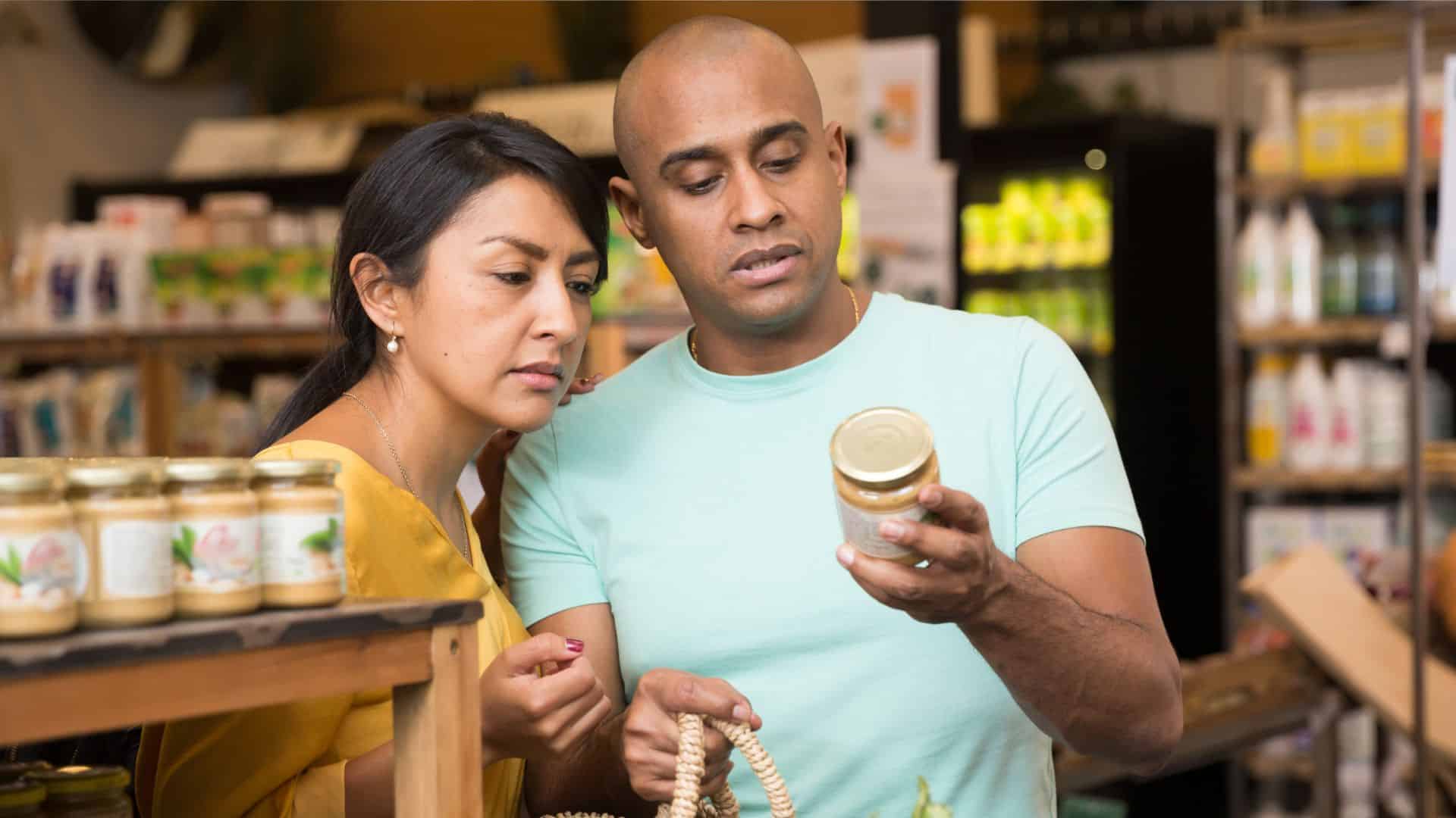 A man and woman reading the nutrition label on a jar.