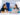 Two women sitting next to eachother at a laptop on a desk. Healthy Living pull up banner sits behind them.