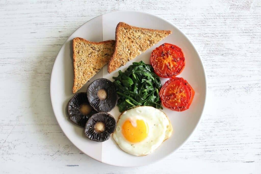 Breakfast featuring egg, mushroom, spinach and tomato with wholegrain toast
