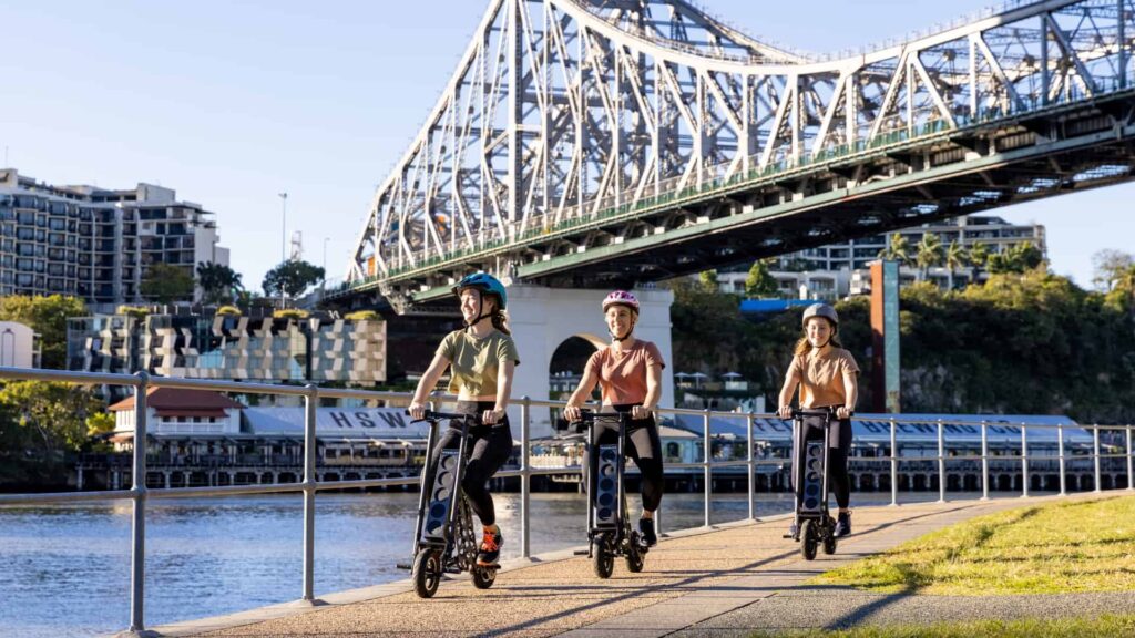 Three woman cycling along a bikeway in a city