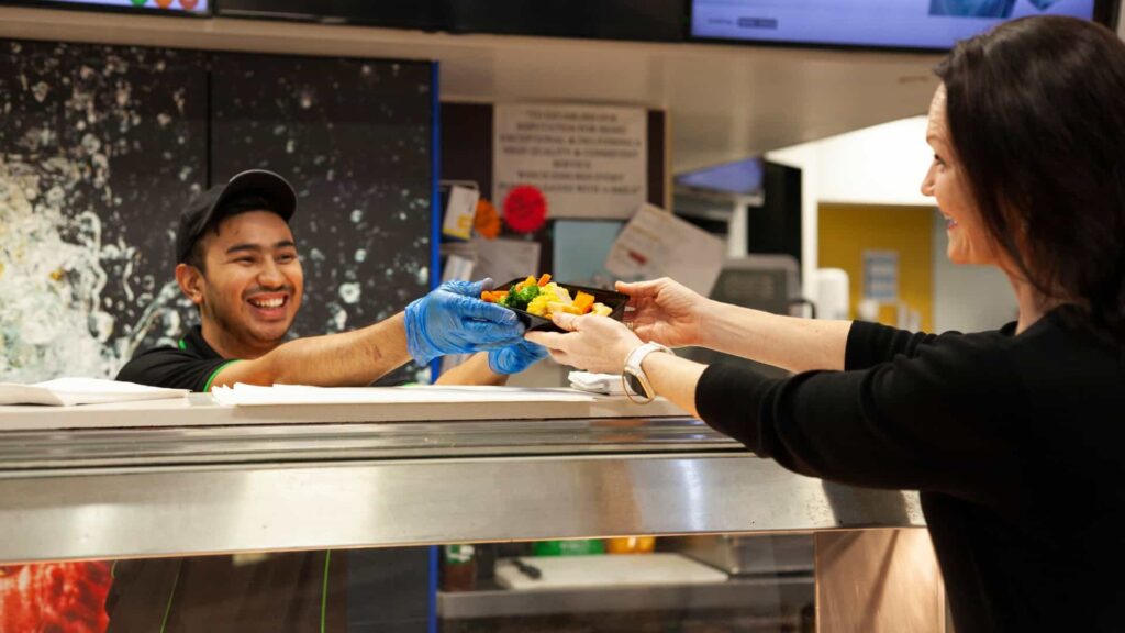 Man serving food to woman over a counter