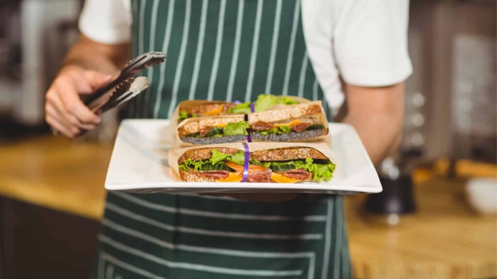 Close up of man holding plate of fresh sandwiches