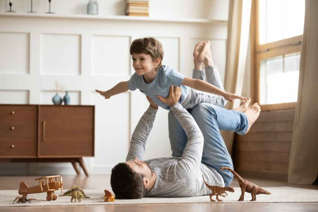 Boy being lifted in air like an airplane by father