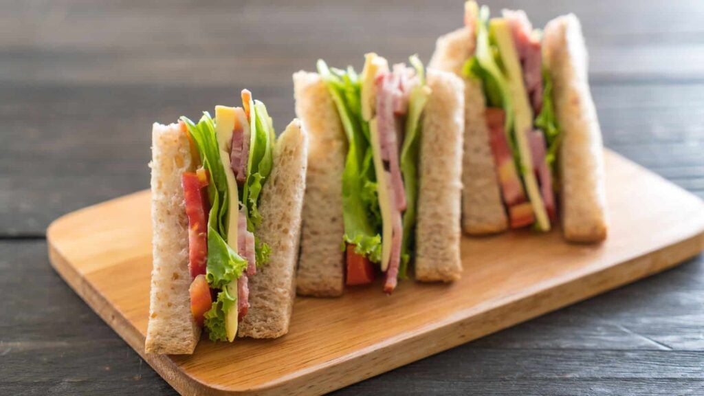 A sandwich made with wholemeal bread, tomatoes, lettuce, cheese and ham.