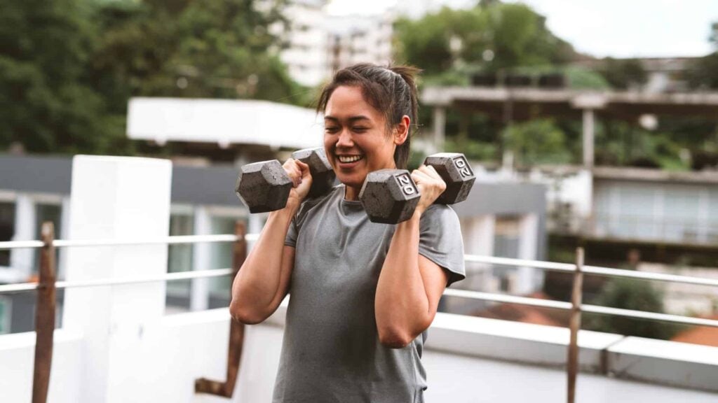 Woman holds tow hand-held weights above her shoulders