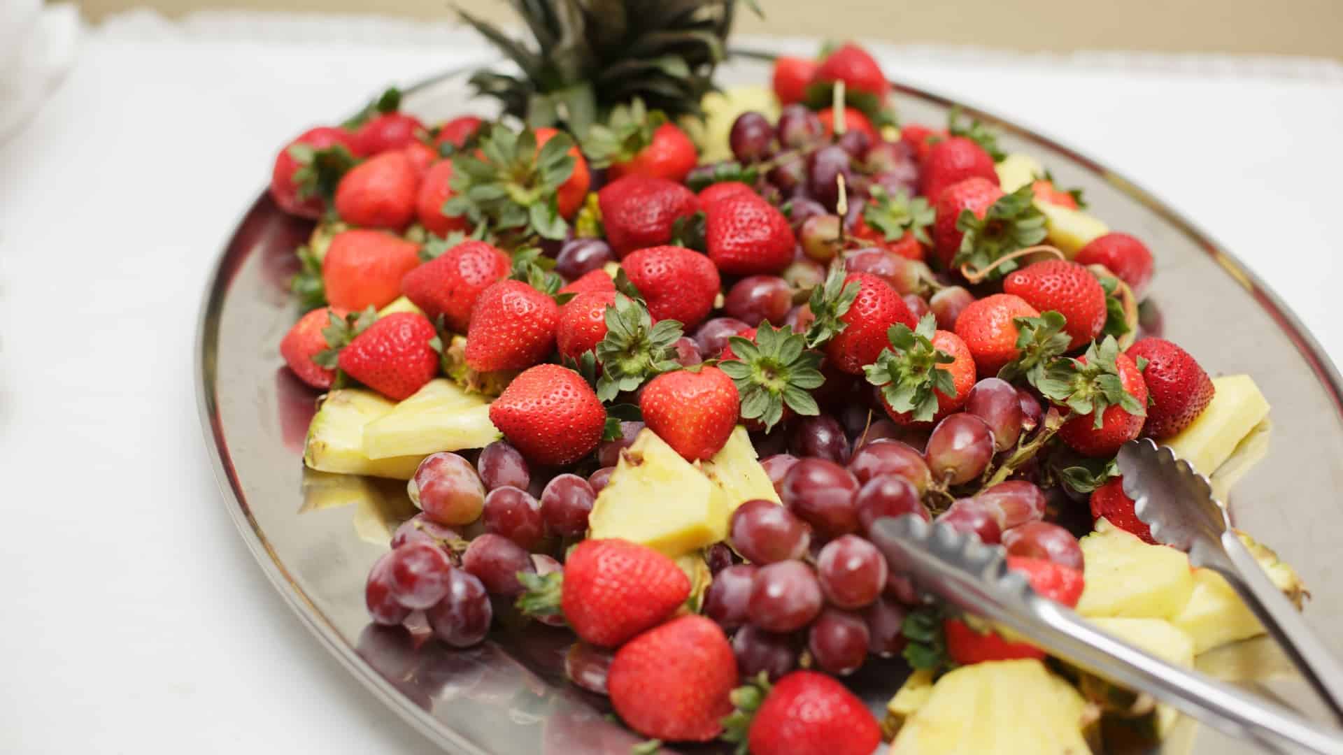 fresh fruit platter featuring strawberries, pineapple and red grapes