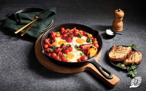 Shakshuka Eggs in a cast iron pan with toasted bread on a side plate