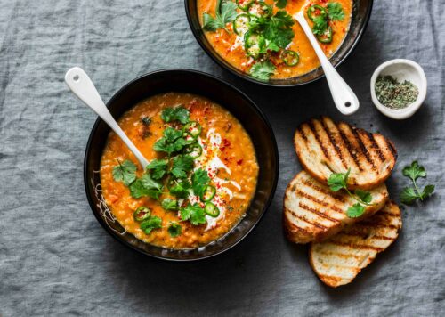 two bowls of coconut lentil soup sprinkles with fresh corriander and a side of toasted bread