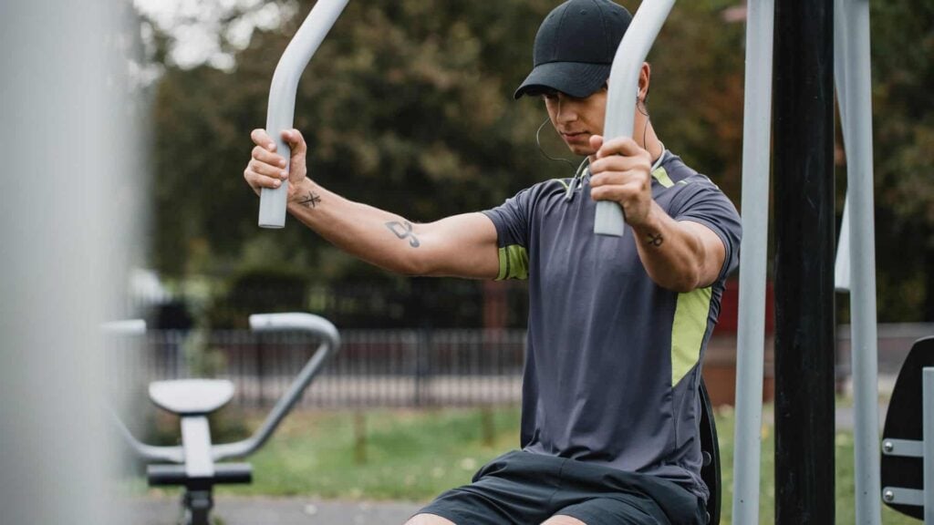 Man uses seated chest press machine as part of an outdoor exercise equipment offering