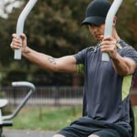 Man uses seated chest press machine as part of an outdoor exercise equipment offering