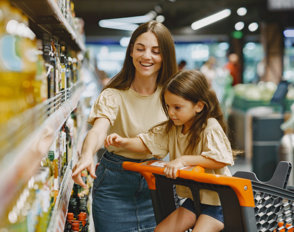 Mother at grocery store with daughter sitting in trolley