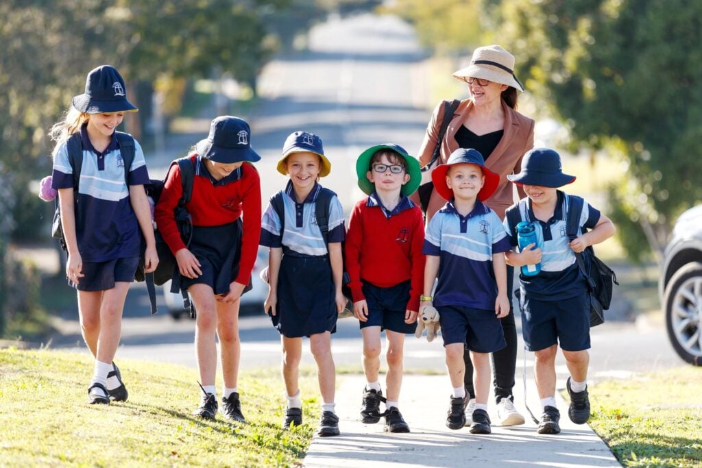 A group of school children walking outside on a footpath.