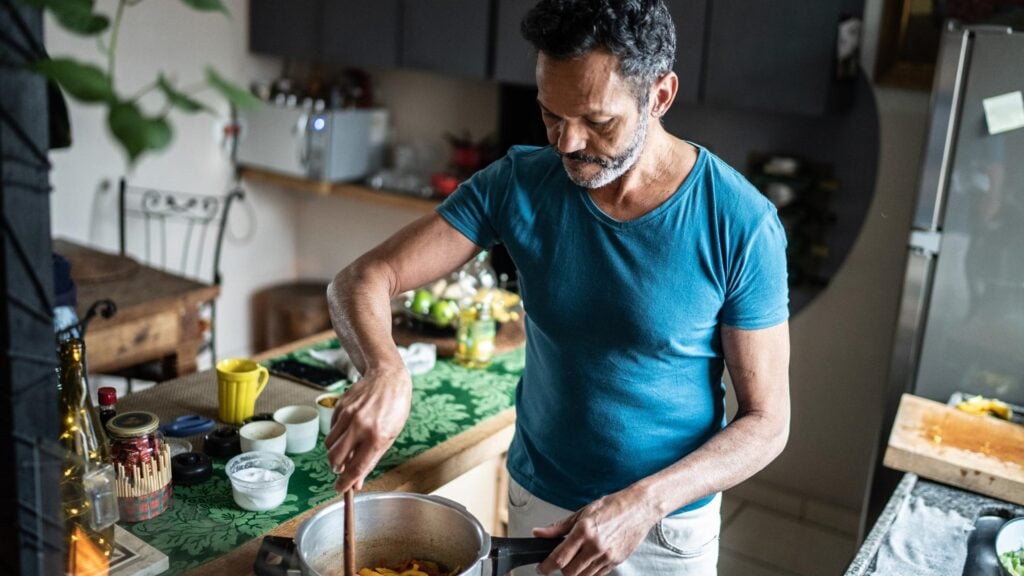 Older man cooks in his kitchen alone