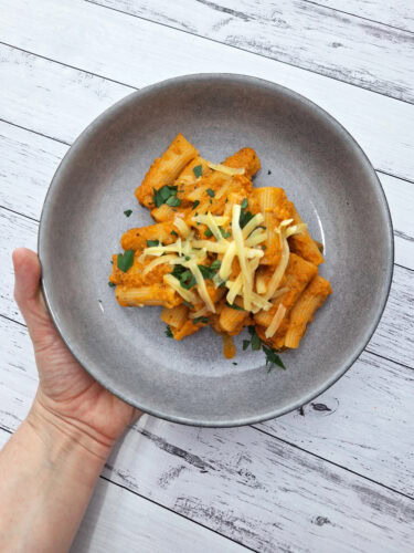 A bowl of pasta covered in creamy vegetable sauce.