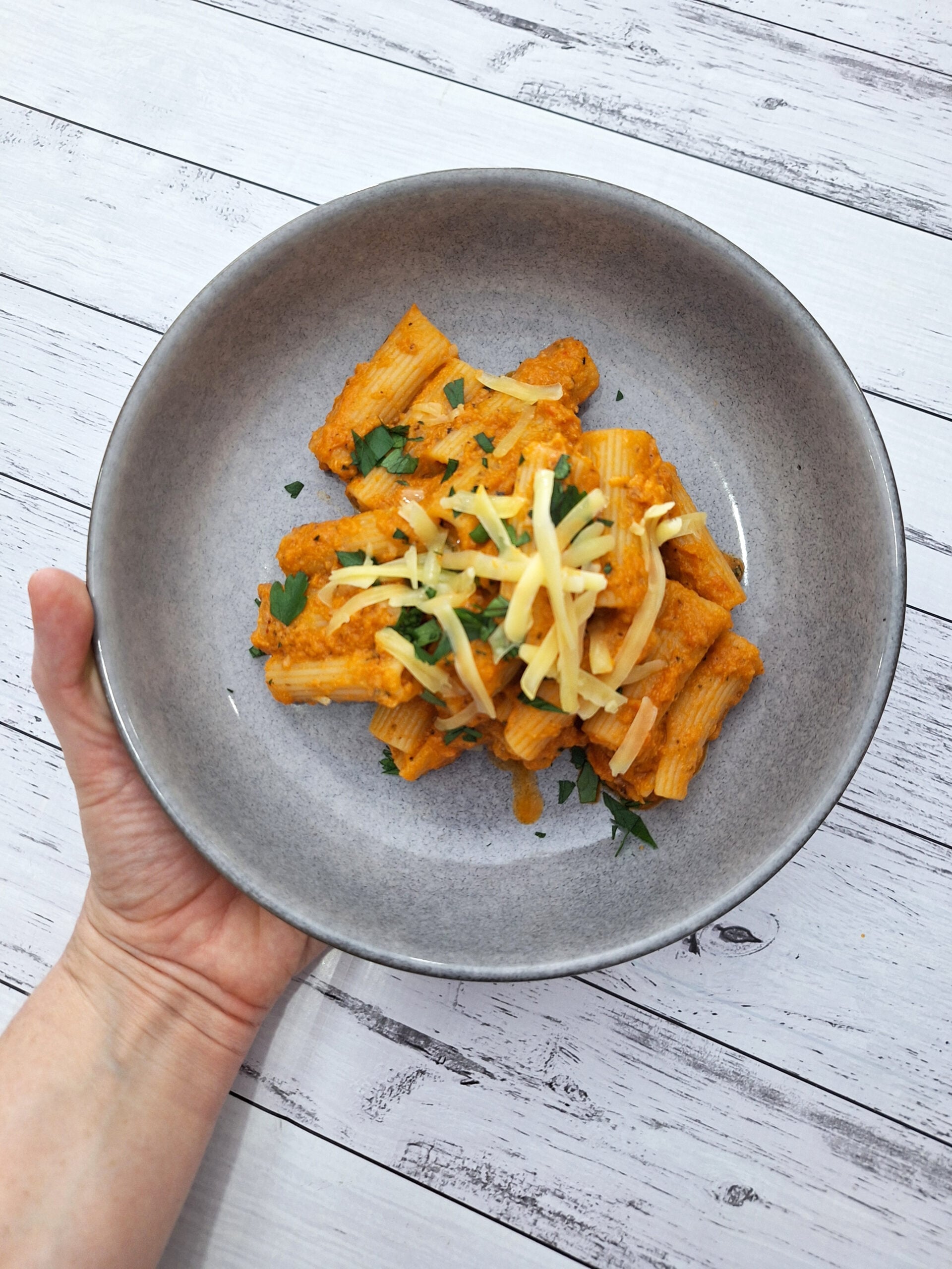 A bowl of pasta covered in creamy vegetable sauce.
