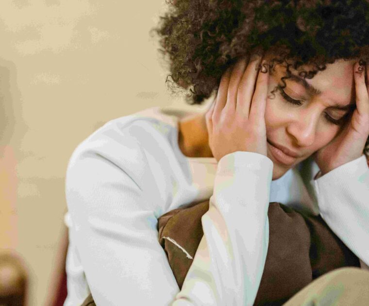 Woman holding head with pillow near chest