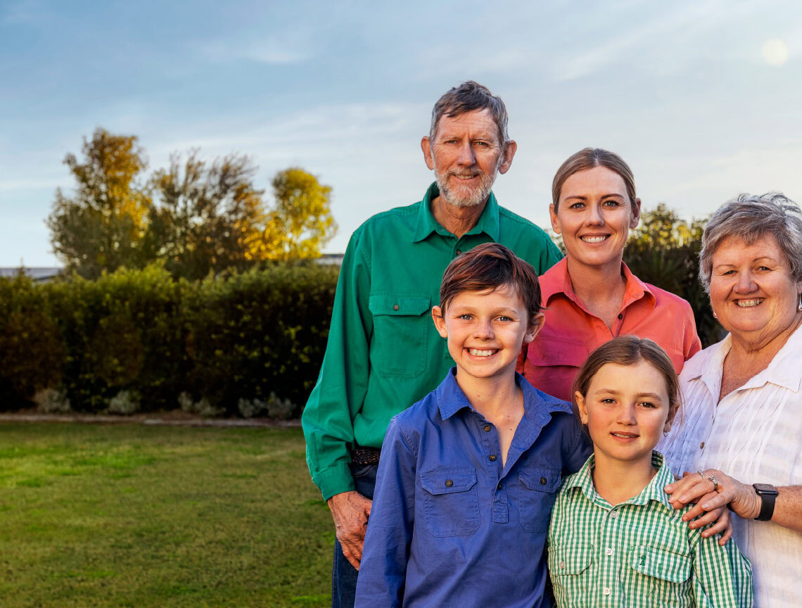 Multi-generational family from Maranoa region stand together outside smiling at the camera
