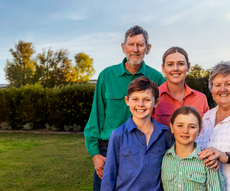 Multi-generational family from Maranoa region stand together outside smiling at the camera