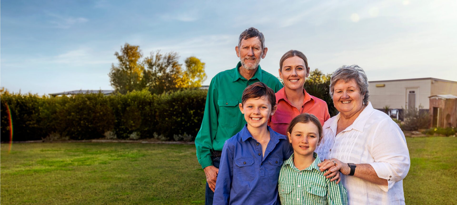Multi-generational family from Maranoa region stand together outside smiling at the camera
