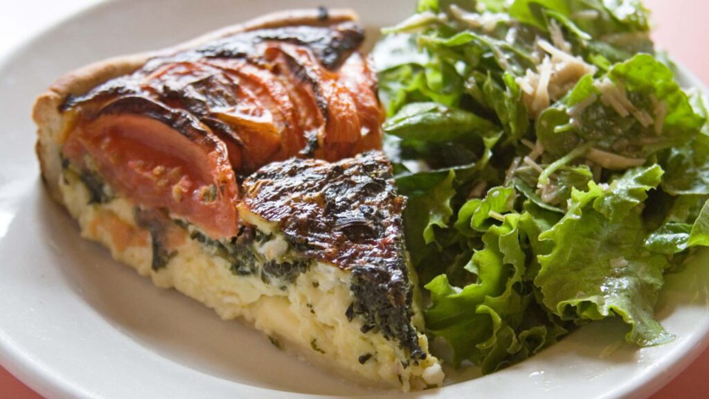 Slide of quiche and green salad on a plate