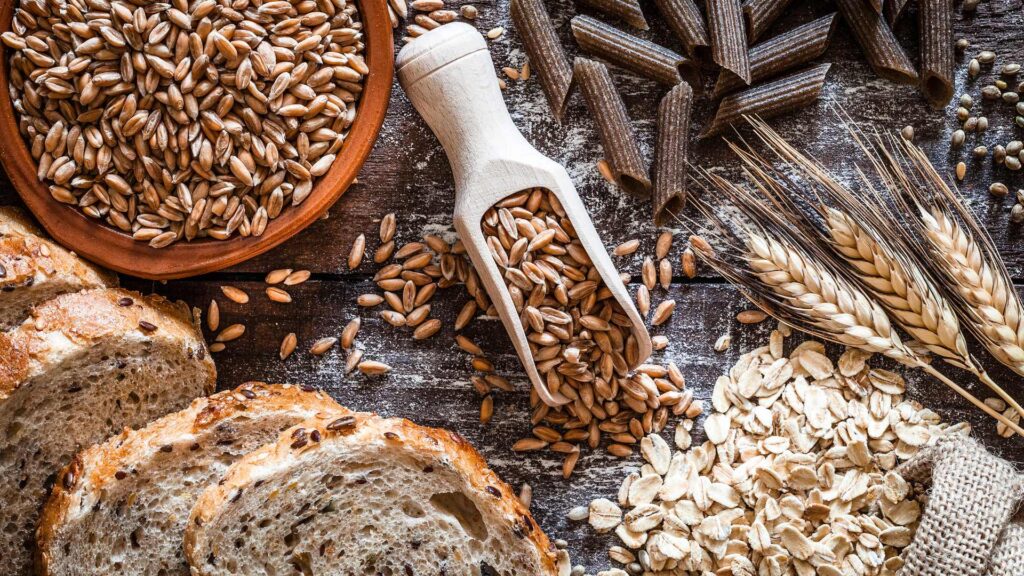 Brown rice, rolled oats, multigrain bread and wholemeal pasta scattered on a flat surface