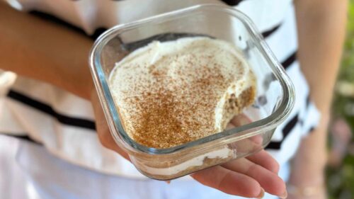 Someone holding a glass container of gingerbread overnight wheat biscuits